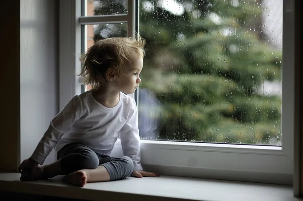 Roztomilé batole dívka při pohledu na dešťové kapky — Stock fotografie