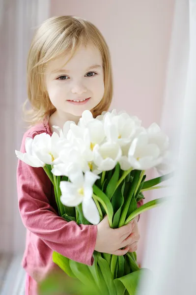 Menina adorável com tulipas pela janela — Fotografia de Stock