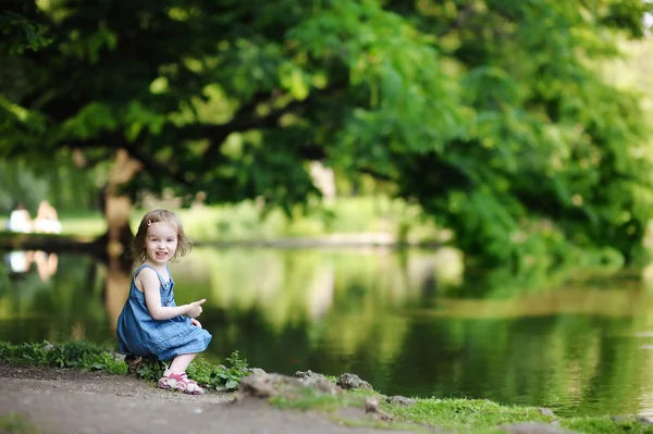 Adorable girl sitting by the water — Stock Photo, Image