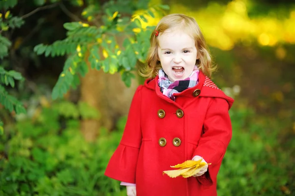 Маленькая девочка в ярко-красном пальто осенью — стоковое фото