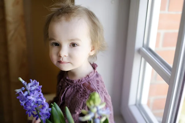 Adorable niña pequeña sentada junto a la ventana — Foto de Stock