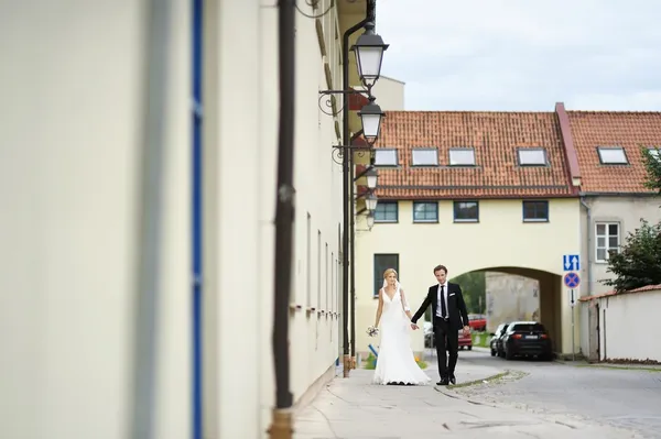 Bride and groom walking in a town — Stock Photo, Image