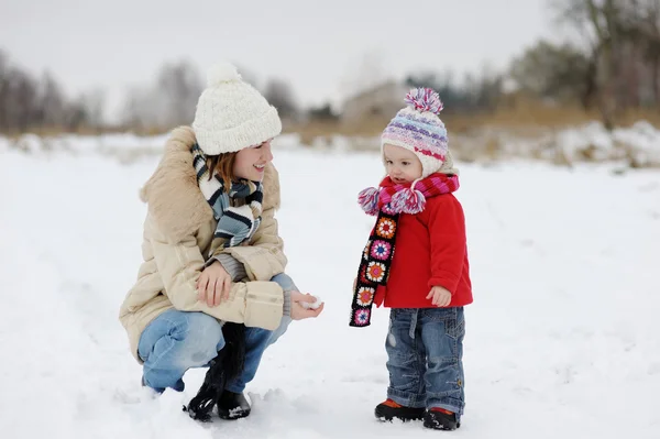 Pequena menina de inverno e sua jovem mãe — Fotografia de Stock