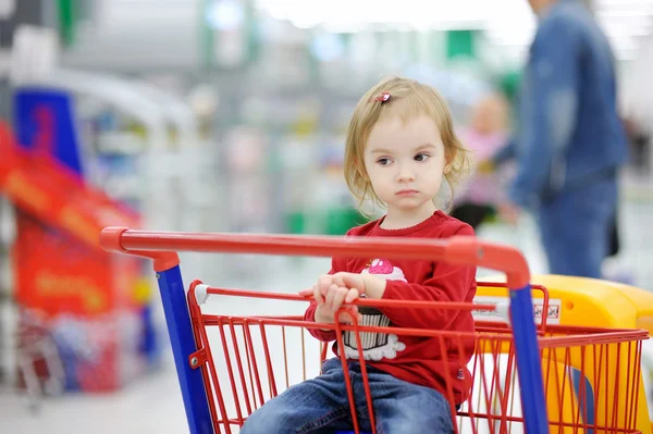 Niño adorable sentado en el carrito de la compra — Foto de Stock