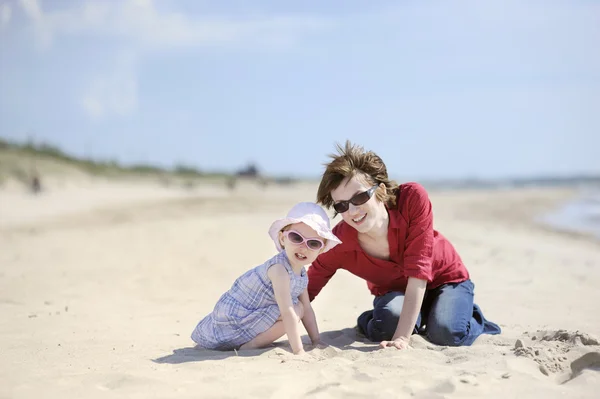 Adorable niña pequeña y su madre en una playa — Foto de Stock