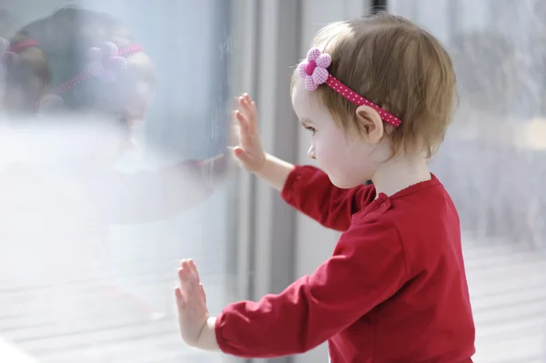 Piccola bambina che guarda attraverso una finestra — Foto Stock