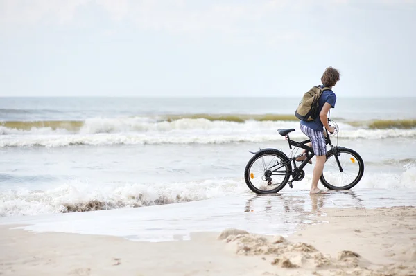 Young man bicycling along al beach — Stock Photo, Image