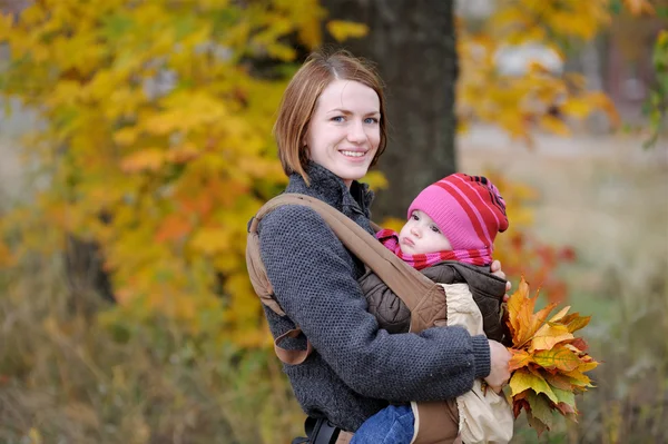 Young mother and her baby in a carrier — Stock Photo, Image