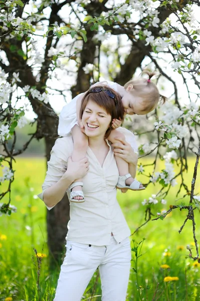 Jovem mãe e sua filha em árvores florescentes — Fotografia de Stock