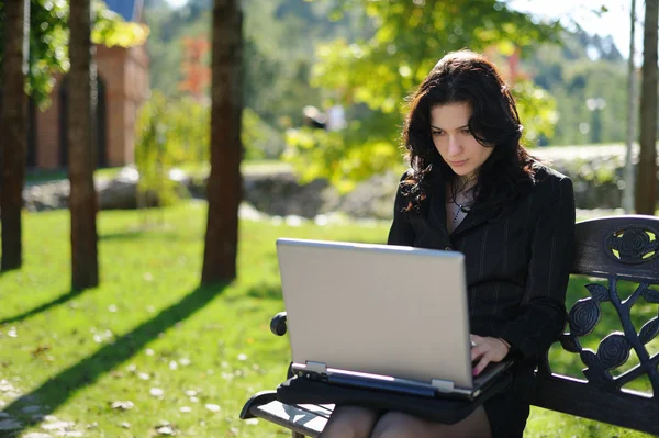 Giovane signora con un quaderno in un parco — Foto Stock