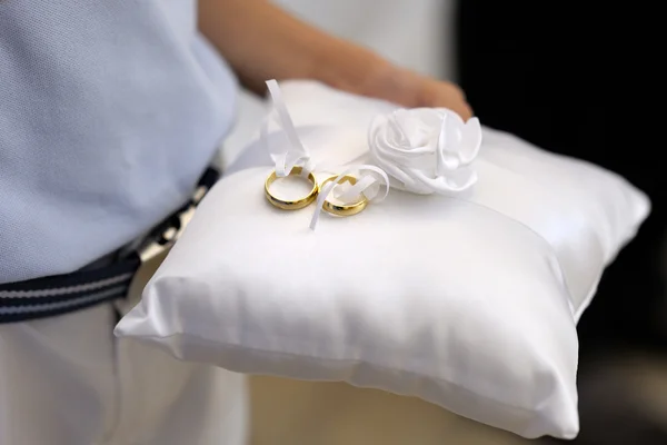 Niño sosteniendo una almohada con los anillos de boda — Foto de Stock