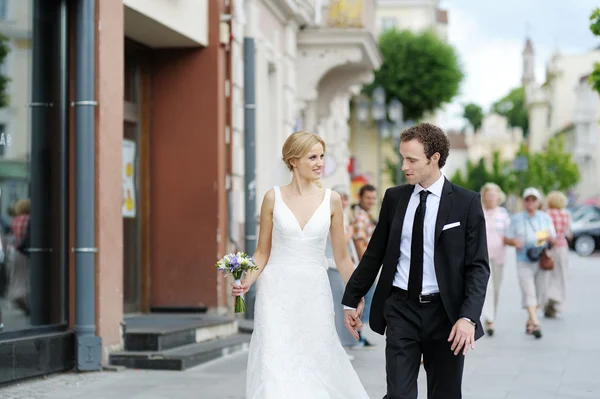 Bride and groom walking in a town — Stock Photo, Image