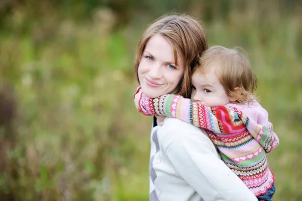 En tjej som har en piggyback tur på sin mamma — Stockfoto