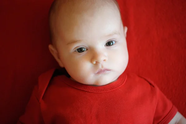 Bebé de dos meses acostado sobre una manta roja —  Fotos de Stock