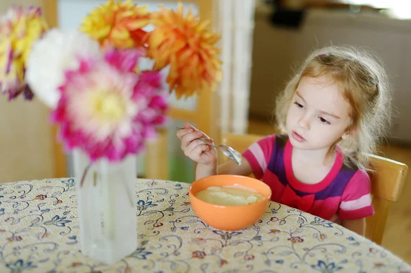 Little girl with a spoon of porridge — Stock Photo, Image