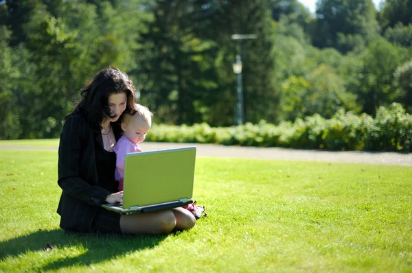 Giovane signora con un bambino e un quaderno in un parco — Foto Stock