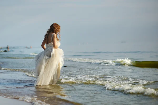 Bride walking along sea coast — Stock Photo, Image