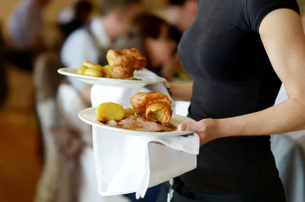 Официантка несет две тарелки с мясным блюдом — стоковое фото