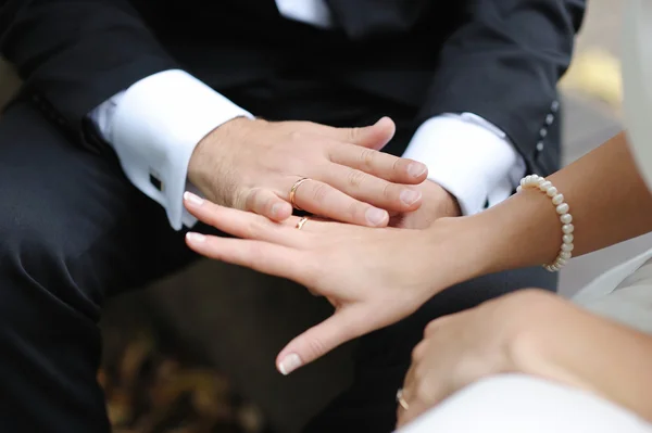 Mãos de noiva e noivo com as alianças de casamento — Fotografia de Stock