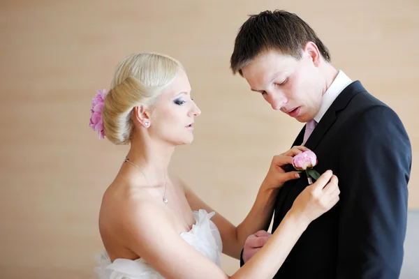 Bride adjusting groom's boutonniere — Stock Photo, Image