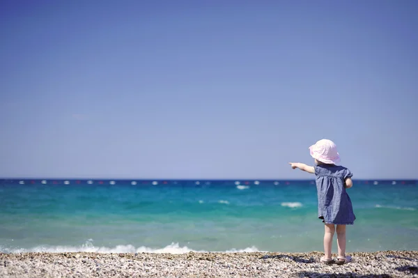 Adorable girl on a pebble beach — Stock Photo, Image