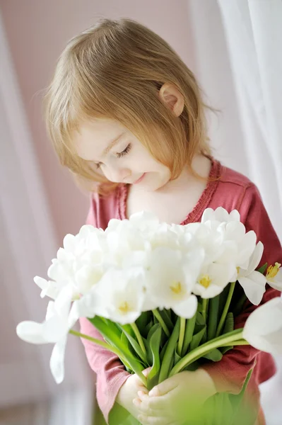Entzückendes kleines Mädchen mit Tulpen am Fenster — Stockfoto