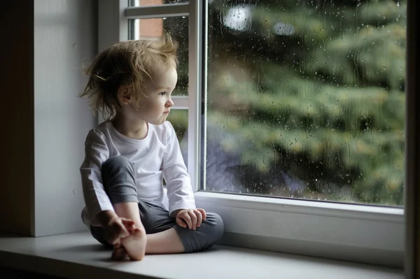 Adorable toddler girl looking at raindrops — Stock Photo, Image