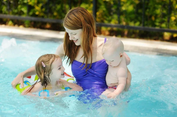 Mother and two daughters swimming in pool Stock Picture