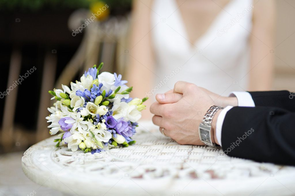 Groom's hands and wedding bouquet