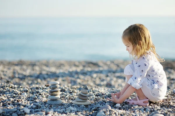 Cute girl playing on pebble beach — Stock Photo, Image