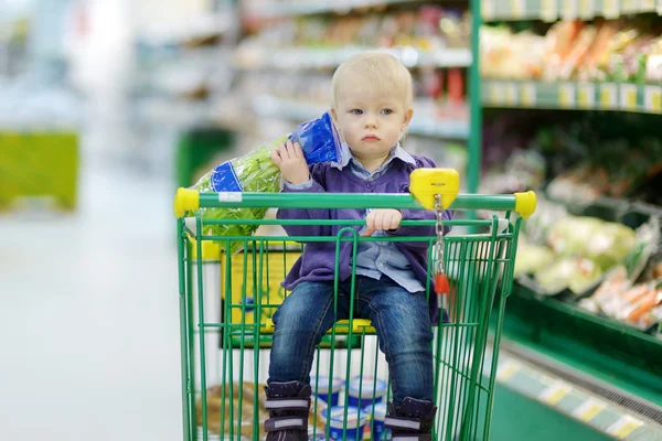 Adorable girl sitting in shopping cart — Stock Photo, Image