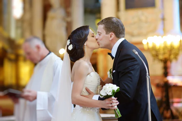 Braut und Bräutigam küssen sich in einer Kirche — Stockfoto