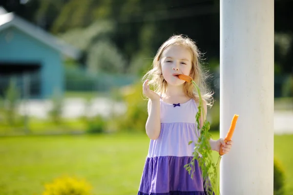 Красивая маленькая девочка с морковкой — стоковое фото