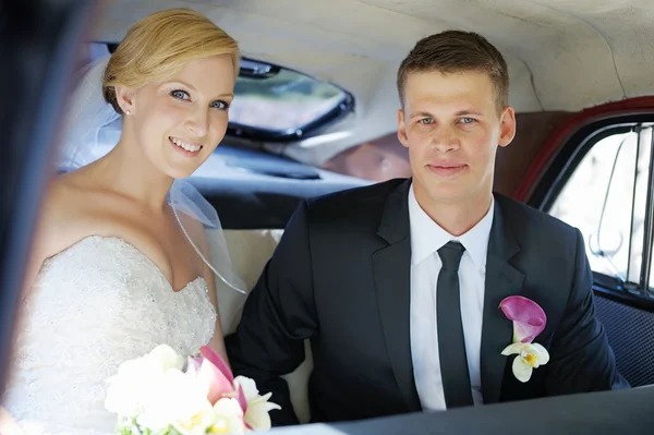 Noiva e noivo sentados em um carro — Fotografia de Stock