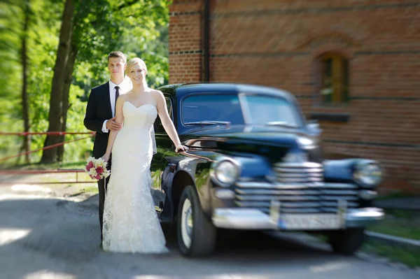 Novia y novio posando en un coche — Foto de Stock