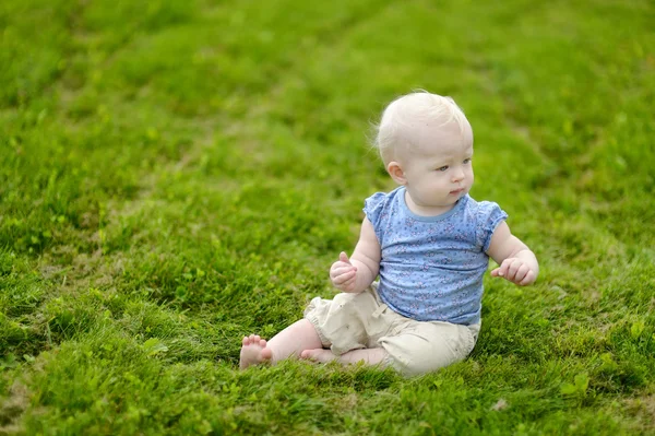 Yeşil çimenlerin üzerinde oturan bebek — Stok fotoğraf