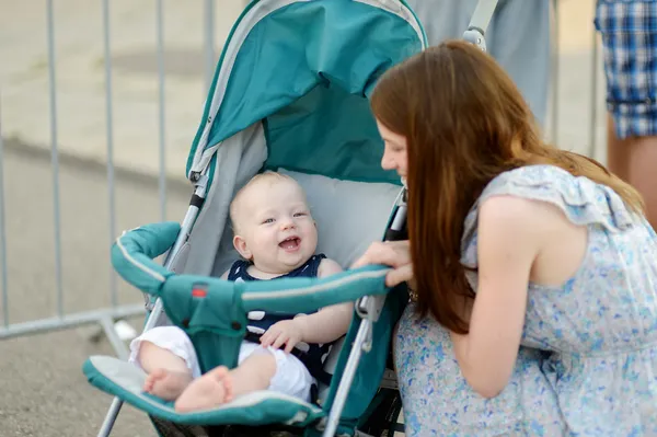 Jovem mãe conversando com seu bebê em um carrinho — Fotografia de Stock