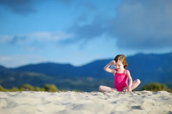 Entzückendes kleines Mädchen spielt an einem Sandstrand — Stockfoto