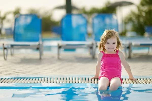 Adorable niña sentada junto a una piscina — Foto de Stock
