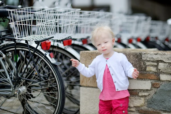 Roztomilá dívka stojící v řadě jízdních kol — Stock fotografie