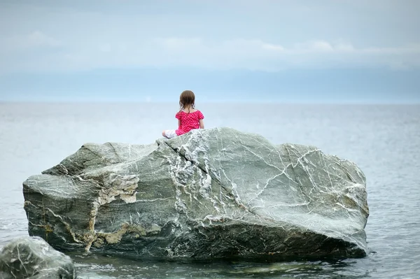 Adorável menina sentada em uma rocha — Fotografia de Stock