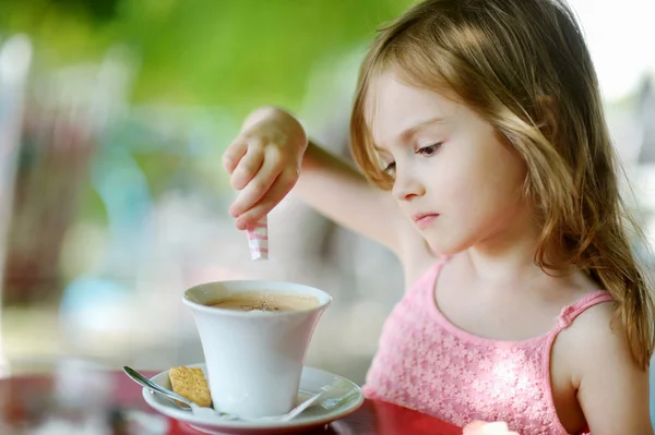 Kleines Mädchen gießt Zucker in heiße Schokolade — Stockfoto