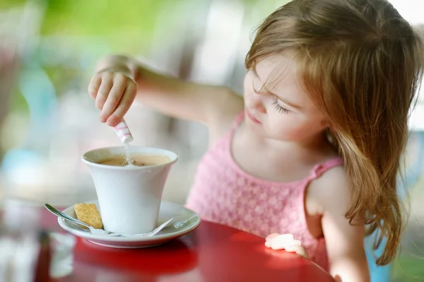 Kleines Mädchen gießt Zucker in heiße Schokolade — Stockfoto