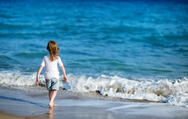Suloinen pieni tyttö hiekkarannalla — kuvapankkivalokuva