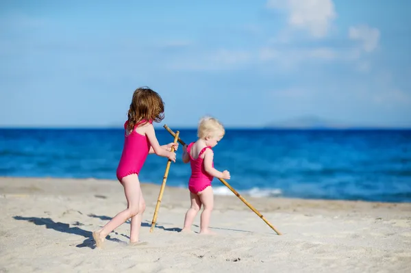 Zwei Schwestern spielen an einem Sandstrand — Stockfoto