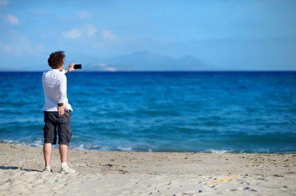 Man taking photo with cell phone on the beach — Stock Photo, Image
