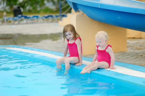 Twee zussen zitten door een zwembad — Stockfoto
