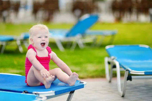Adorable toddler girl sitting on a sunbed — Stock Photo, Image