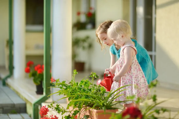 Two little sisters watering flowers — Stock Photo, Image
