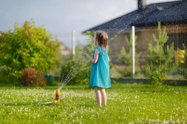 Gadis berjalan meskipun sprinkler — Stok Foto